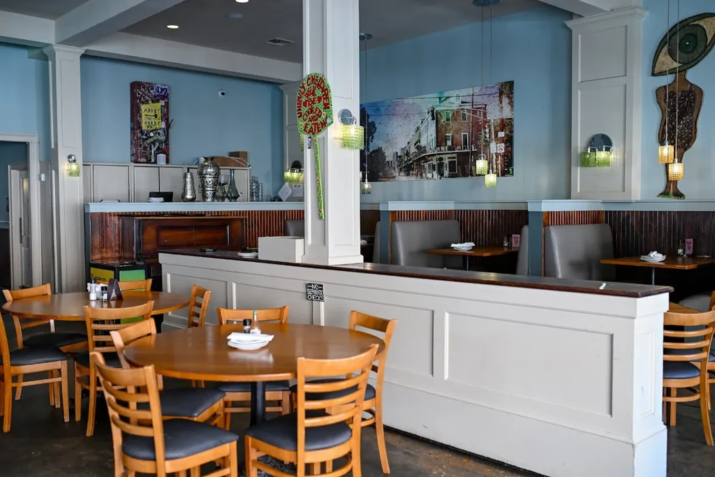 Empty, brightly lit casual restaurant interior with diverse seating and wall art.
