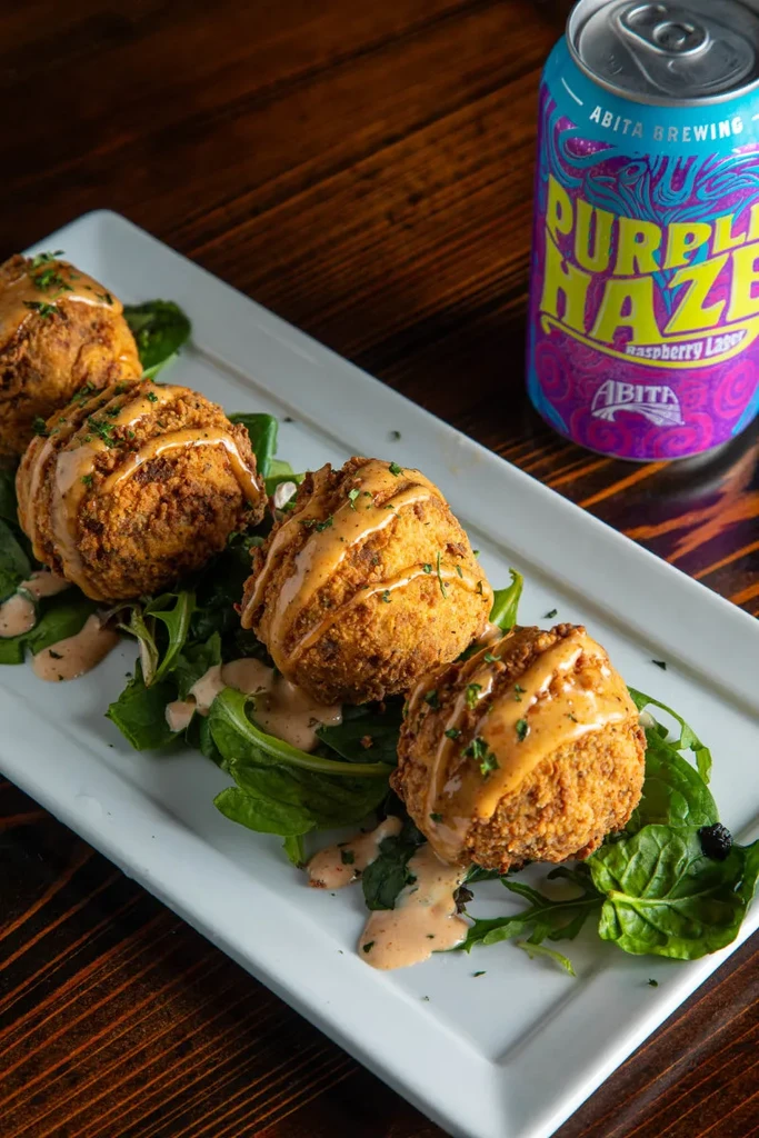 Four fried food items with sauce, herbs, and "Purple Haze" lager.