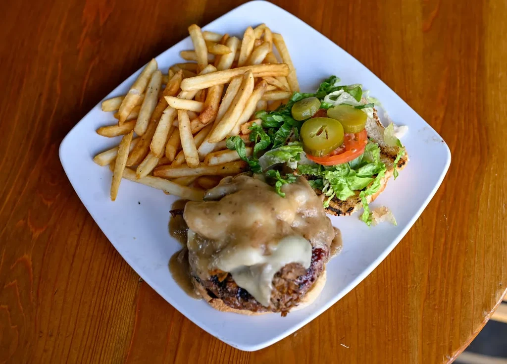 Overhead view: burger with gravy, melted cheese, fries, and salad.