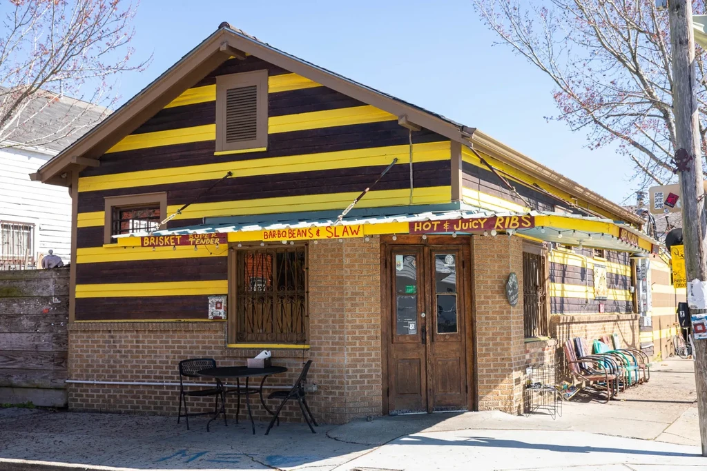 Yellow and brown striped restaurant with food signs and outdoor seating.