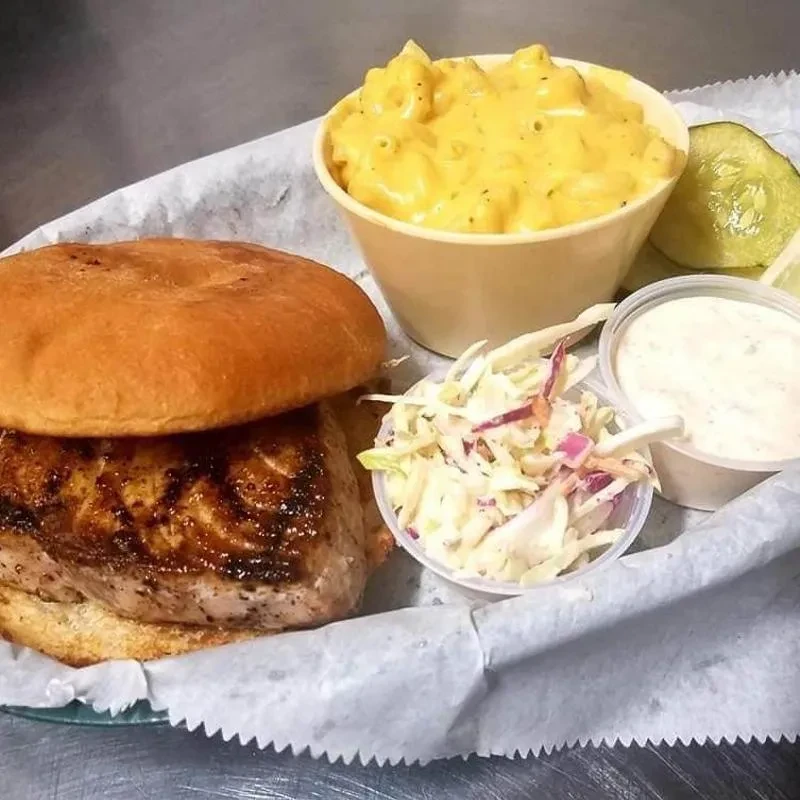 Grilled fish sandwich meal with mac and cheese, coleslaw, and sauce.
