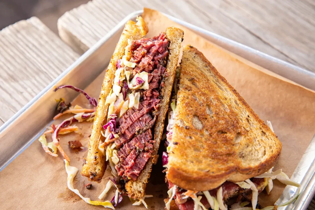 Generously filled meat and coleslaw sandwich on toasted bread.