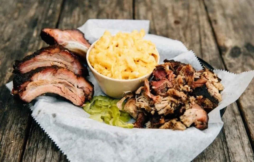 Barbecue platter: smoked ribs, mac and cheese, pulled meat, and pickles.