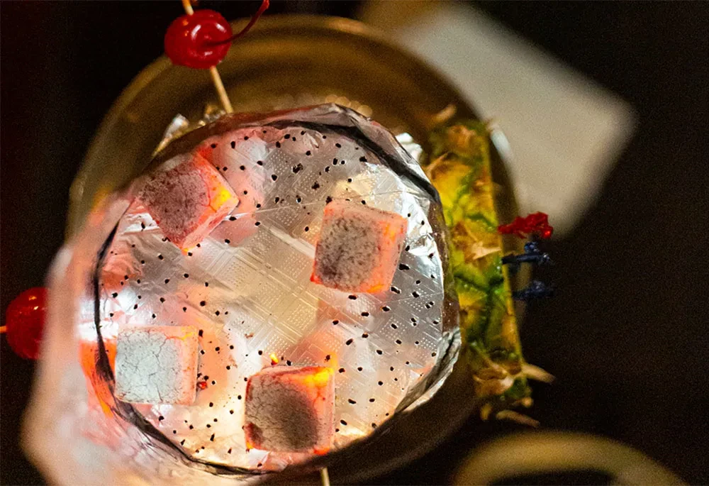 Hookah head with glowing charcoal, red cherries, and pineapple decor.