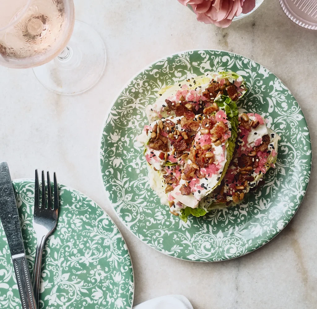 Top-down: Lettuce wraps with creamy dressing, bacon, seeds, pink pickled ingredients.