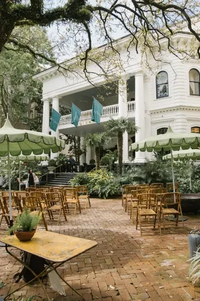 White mansion with outdoor event chairs, umbrellas, and teal club flags.