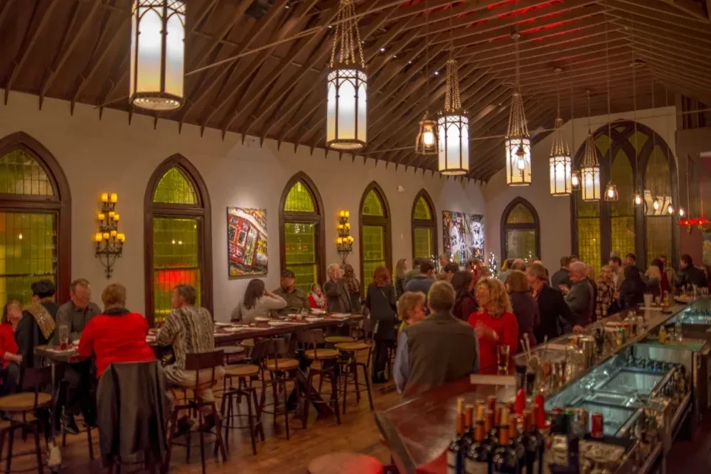 Spacious restaurant with vaulted wooden ceilings, Gothic lanterns, and many patrons.