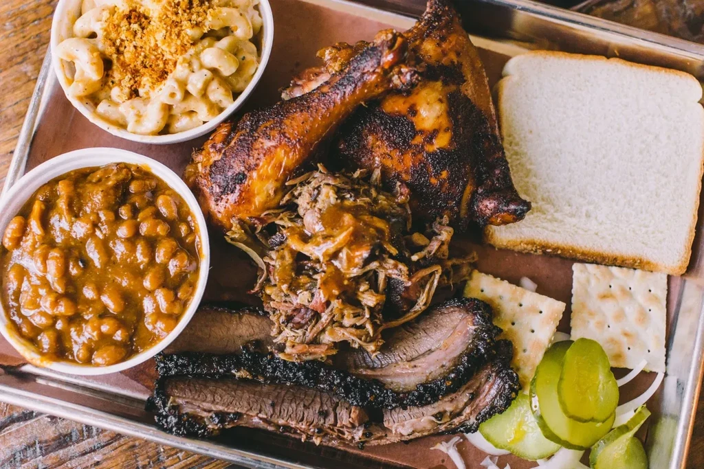 BBQ platter with chicken, pulled pork, brisket, mac and cheese, and beans.