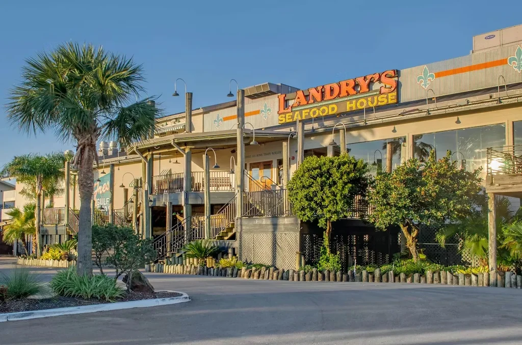 Two-story Landry's Seafood House restaurant with tropical architecture and lush landscaping.