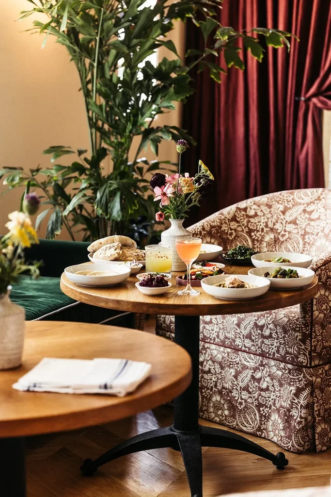 Restaurant table with small dishes, drinks, and a colorful floral centerpiece.
