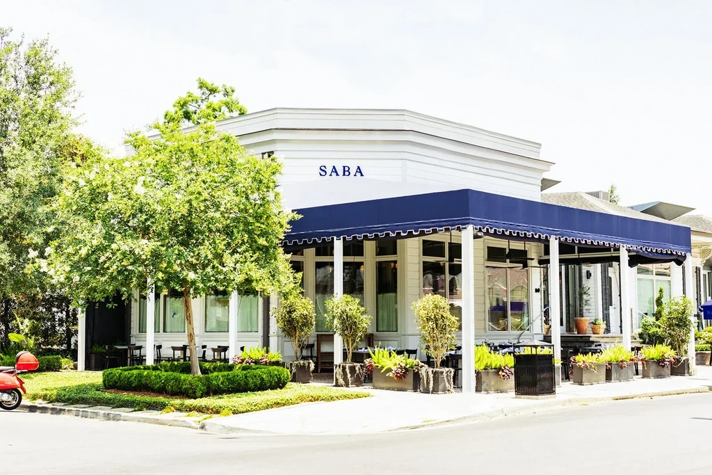 SABA restaurant: white two-story building, dark blue awning, green plants.
