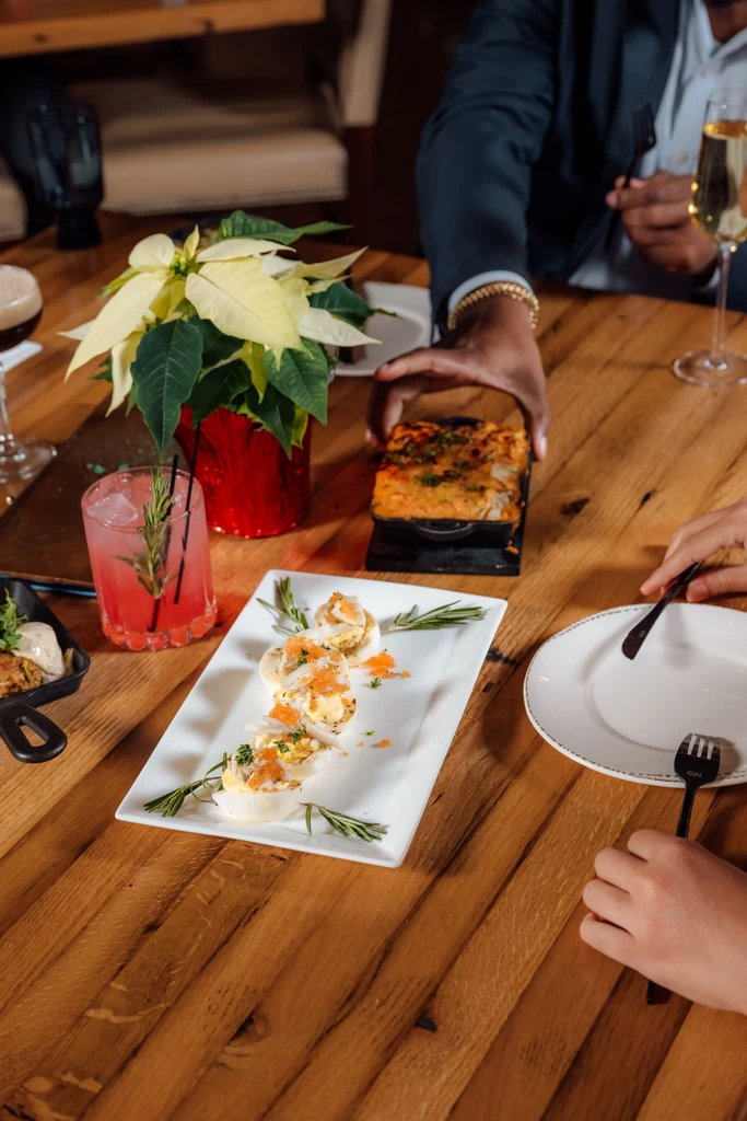 Restaurant table with deviled eggs, pink cocktail, and a poinsettia.