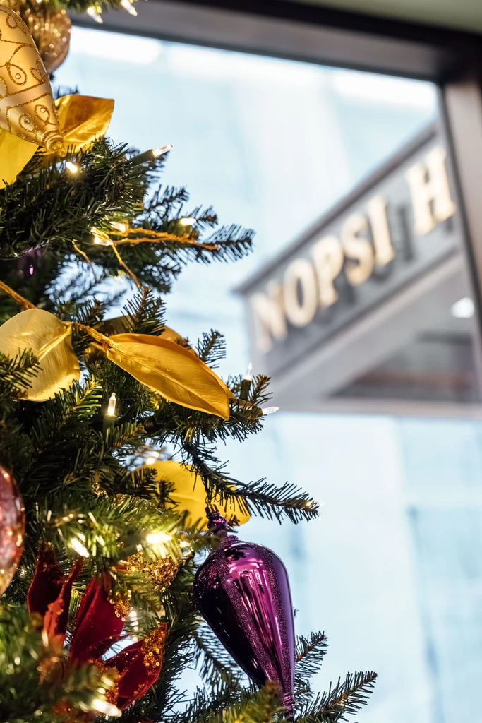 Decorated Christmas tree with prominent purple, gold, red ornaments, white lights.