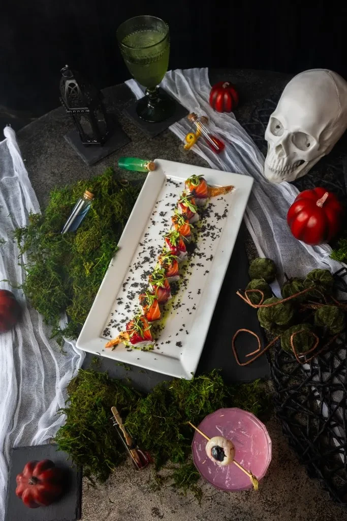 Top-down Halloween table with serpentine food, skull, and eyeball drink.