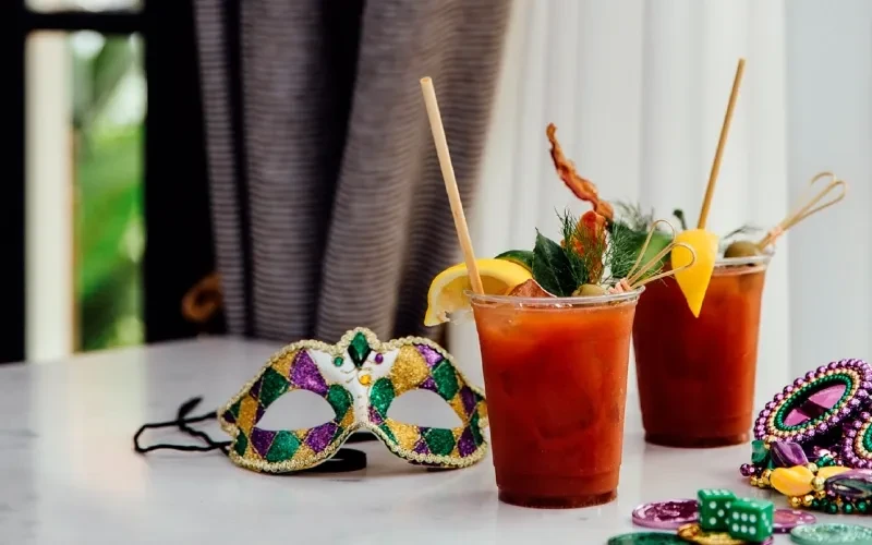 Garnished Bloody Mary cocktails with Mardi Gras mask and beads.