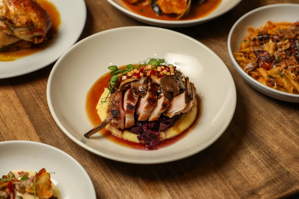 Plated grilled pork chop, yellow purée, cabbage, and other restaurant dishes.