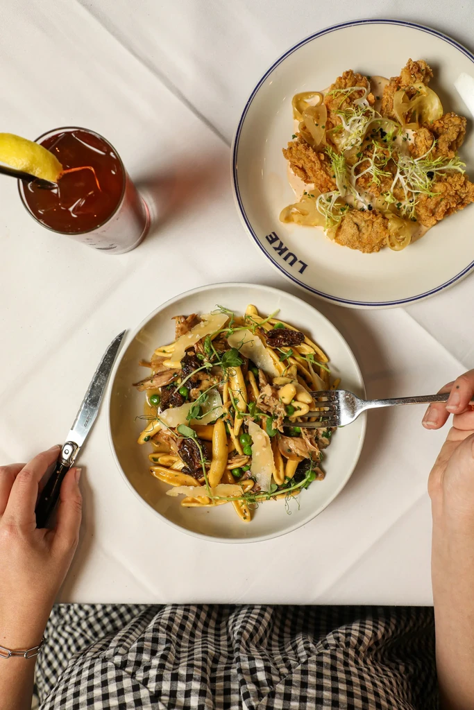 Overhead view: restaurant pasta, fried food, and a red drink.