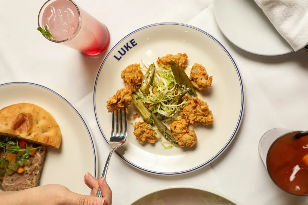 Overhead shot of a dining table with "LUKE" plate, chicken, and drinks.