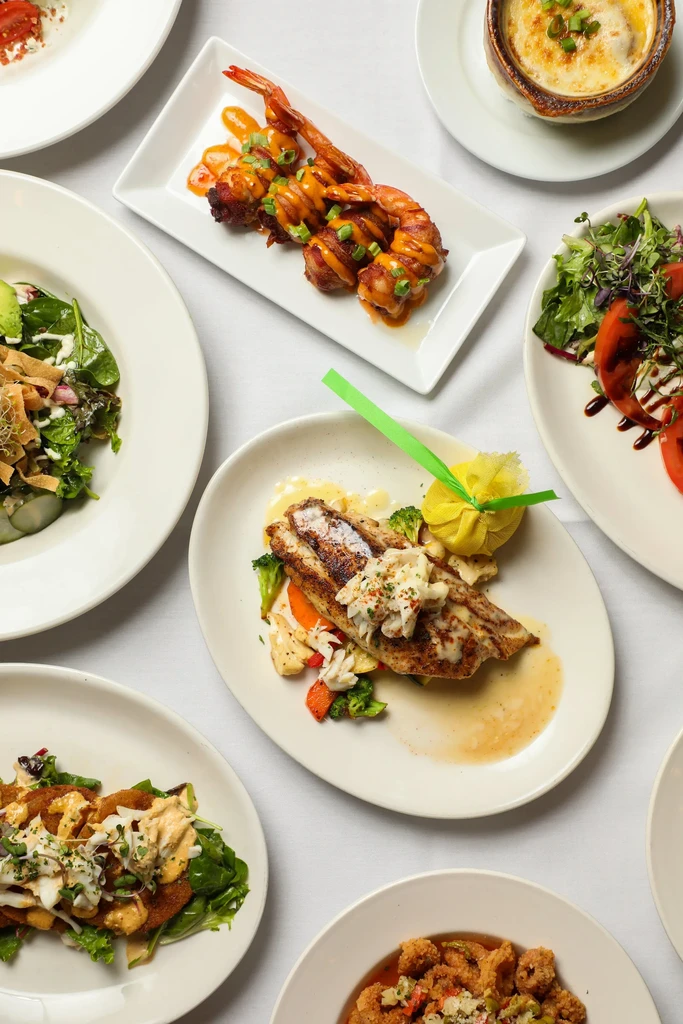 Overhead shot of diverse, attractively plated dishes on a white tablecloth.
