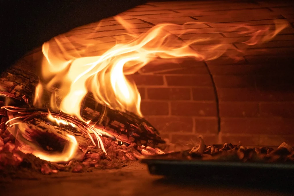 Roaring wood fire in a brick oven, food roasting.