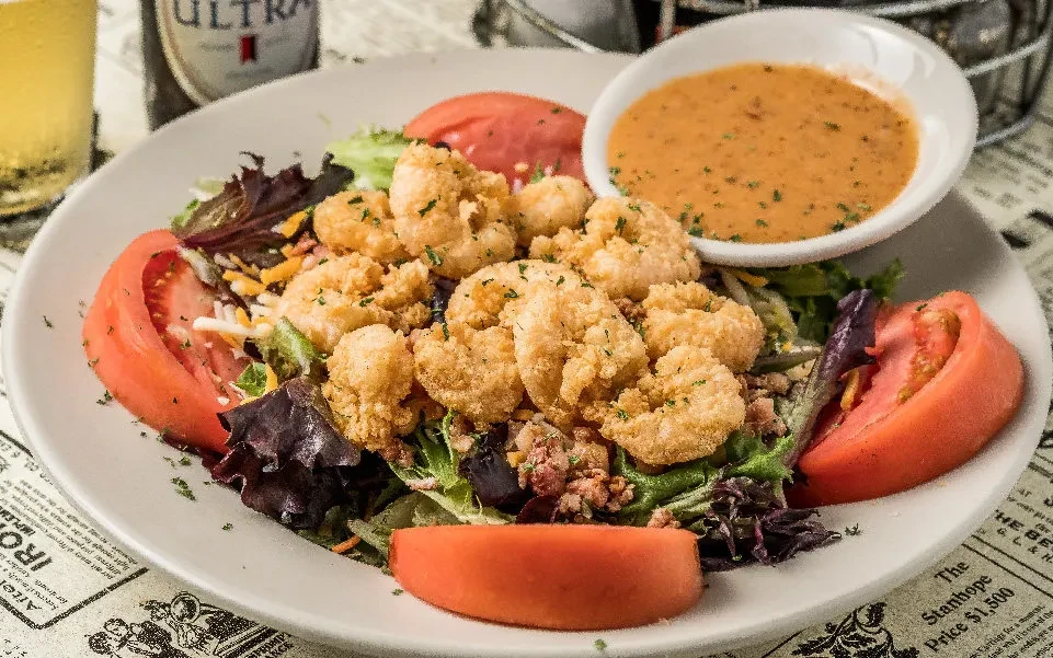 Fried shrimp salad with mixed greens, tomato, cheese, and dressing.