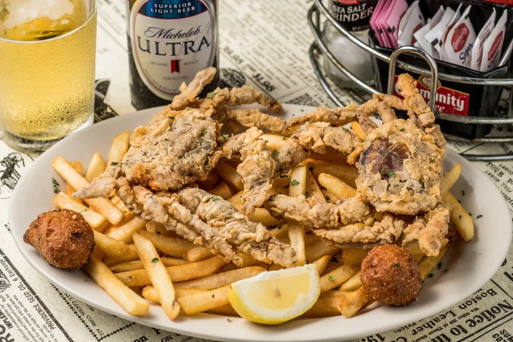 Plate of fried soft-shell crabs, french fries, hushpuppies, and lemon.