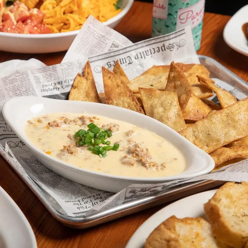 Creamy meat queso dip with tortilla chips, pasta, and garlic bread.