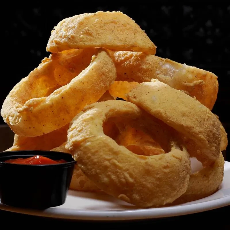 Crispy golden onion rings piled high with a side of ketchup.