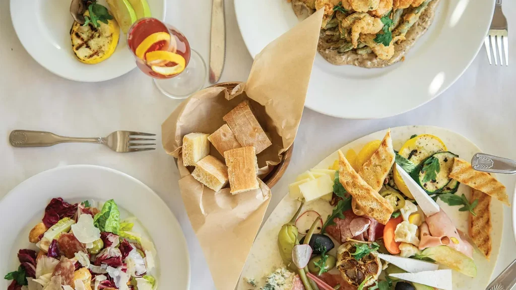 Overhead: Charcuterie, salad, tempura, focaccia, and drink arranged on a table.