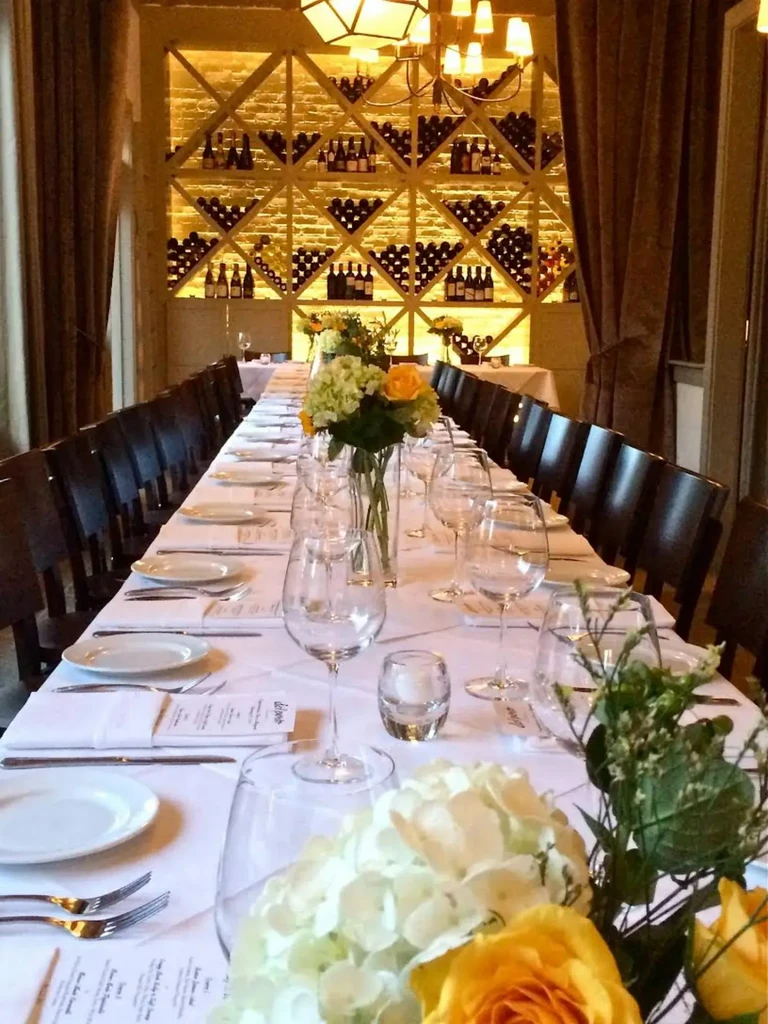 Elegant dining table set with flowers, candles, and a large wine rack.