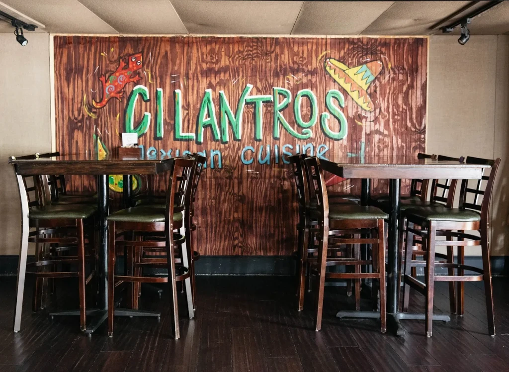 Cilantros Mexican restaurant interior with high-top tables and colorful mural.