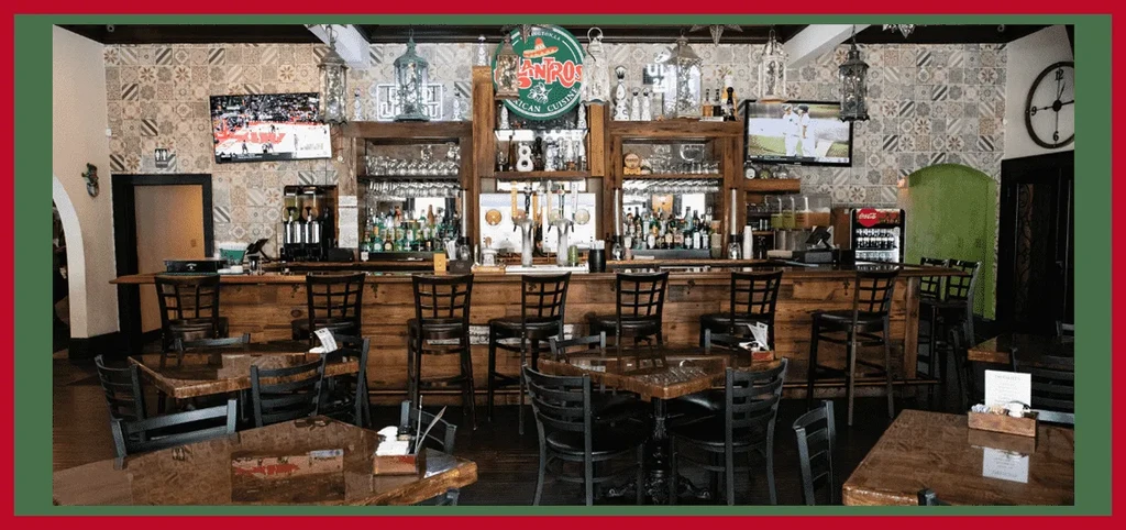 Empty rustic Mexican restaurant interior with a bar and dining tables.
