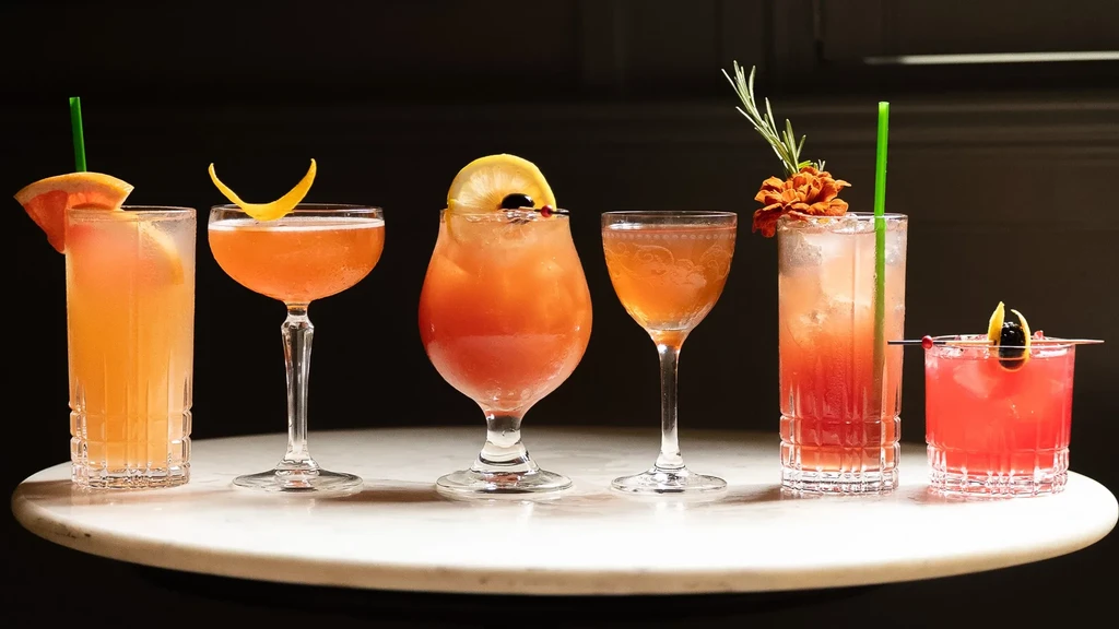 Six artfully arranged cocktails on a white marble table.