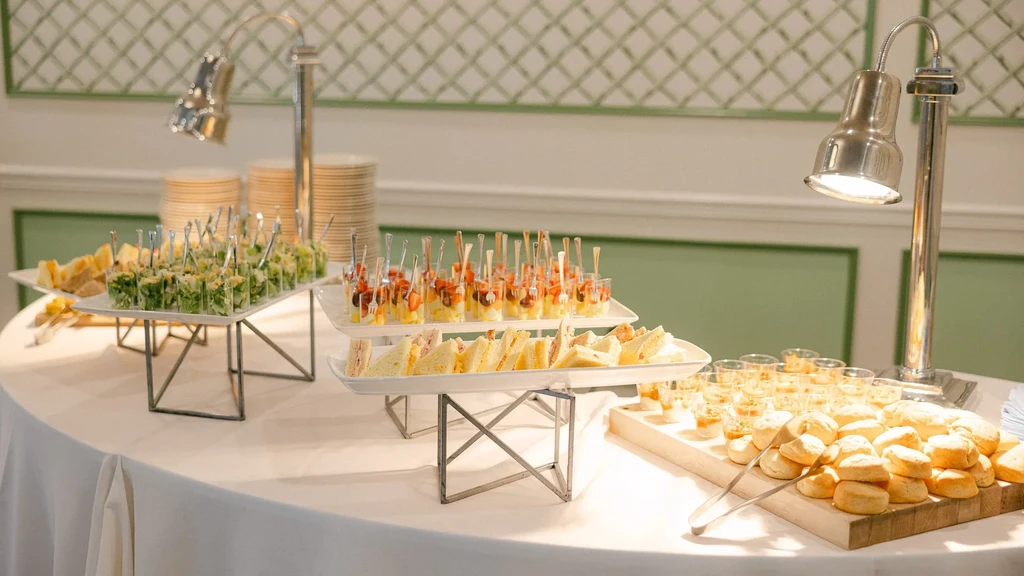 Well-arranged buffet with salads, sandwiches, rolls, desserts, and heat lamps.