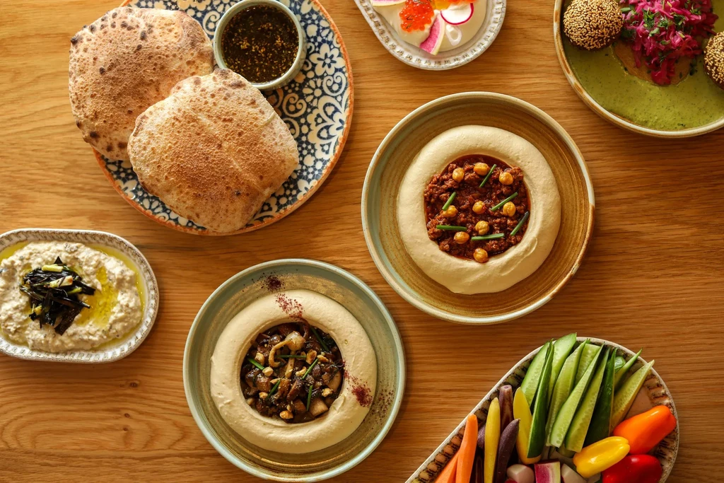 Colorful overhead spread of Middle Eastern and Mediterranean dips and crudités.