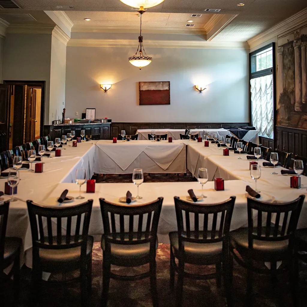 Large U-shaped dining table set in an empty private restaurant.