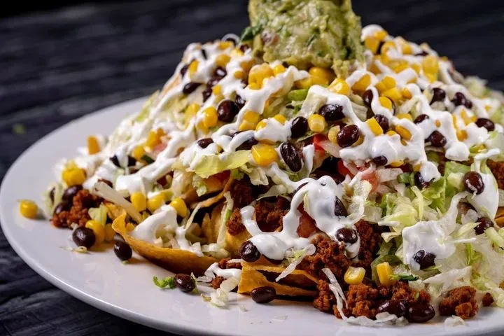 Loaded nachos with meat, vegetables, sour cream, and guacamole.