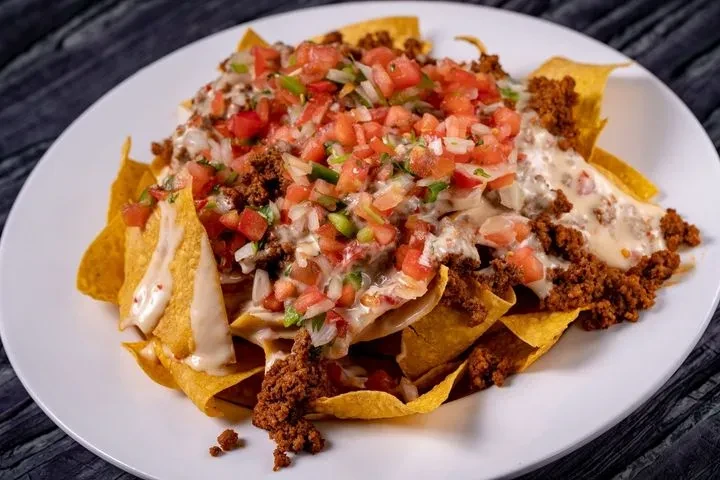 Nachos with abundant cheese, seasoned meat, and fresh pico de gallo.