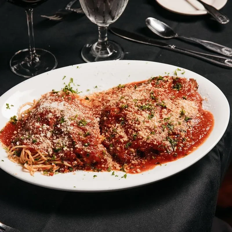 Spaghetti and meatballs covered in red sauce, cheese, and green herbs.