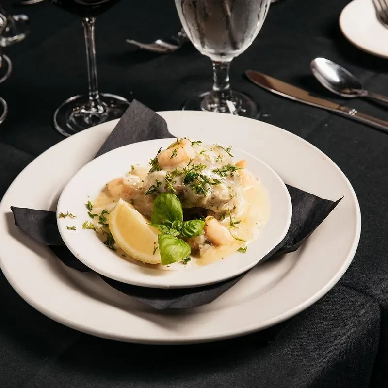 Plated seafood with creamy sauce, fresh herbs, lemon, and shrimp.