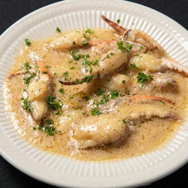Crab claws in creamy brown sauce with chopped green herbs.