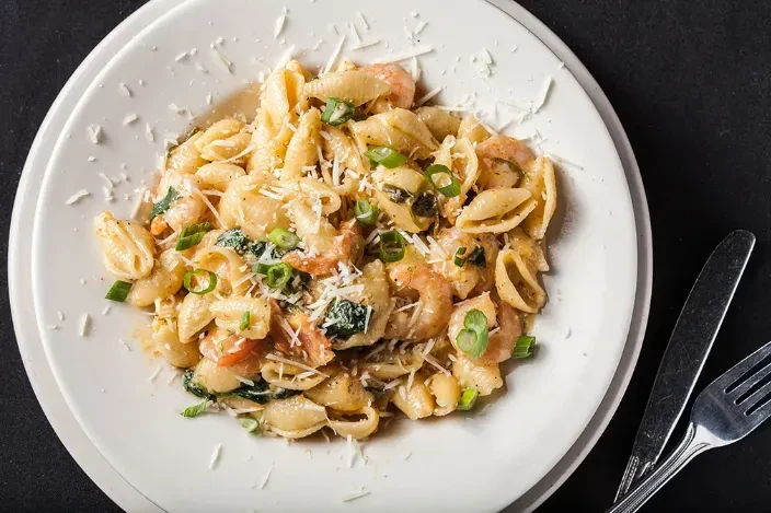 Creamy conchiglie pasta with shrimp, spinach, tomatoes, and Parmesan.