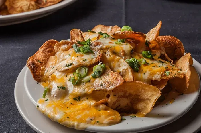 Crispy potato slices topped with melted cheese, green onions, and parsley.