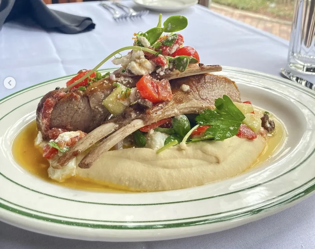 Gourmet lamb chops, purée, tomatoes, feta, herbs on a plate.