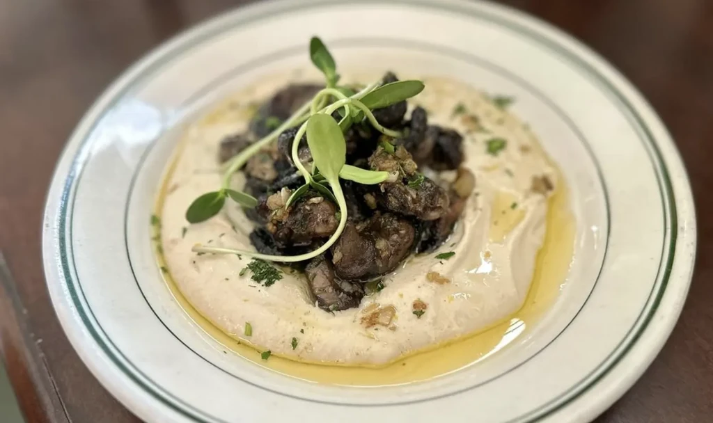 Overhead: Creamy hummus with sautéed mushrooms, microgreens and herbs.