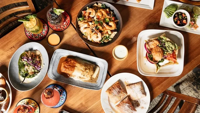 Overhead: assorted plates of Latin American food, desserts, and cocktails.