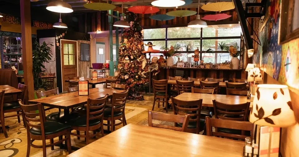 Eclectic restaurant interior with Christmas tree, colorful umbrellas, and artwork.