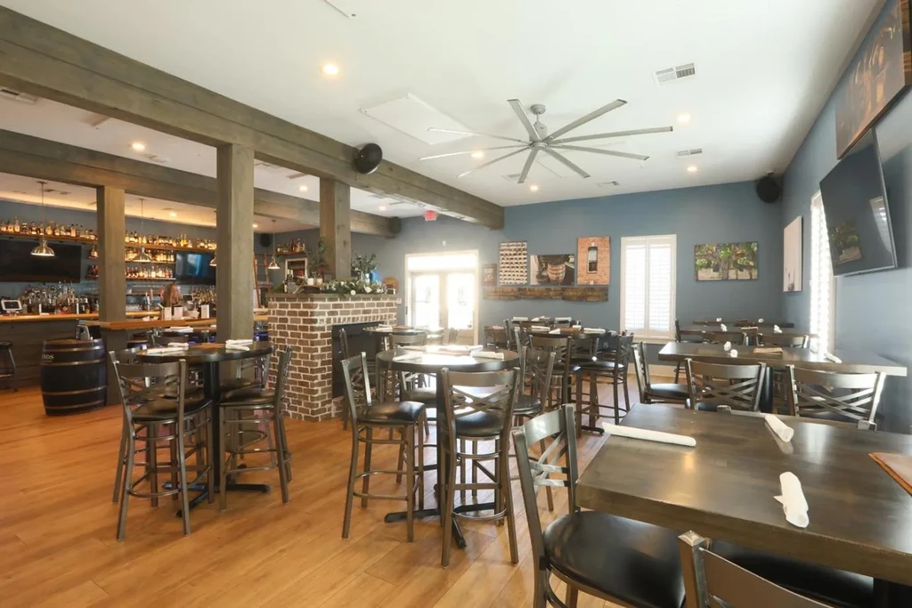 Rustic-modern restaurant interior: blue walls, wood floors, brick fireplace, bar.