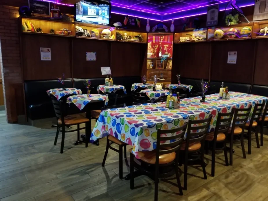 Restaurant party setup with sports memorabilia, colorful tables, and purple neon.