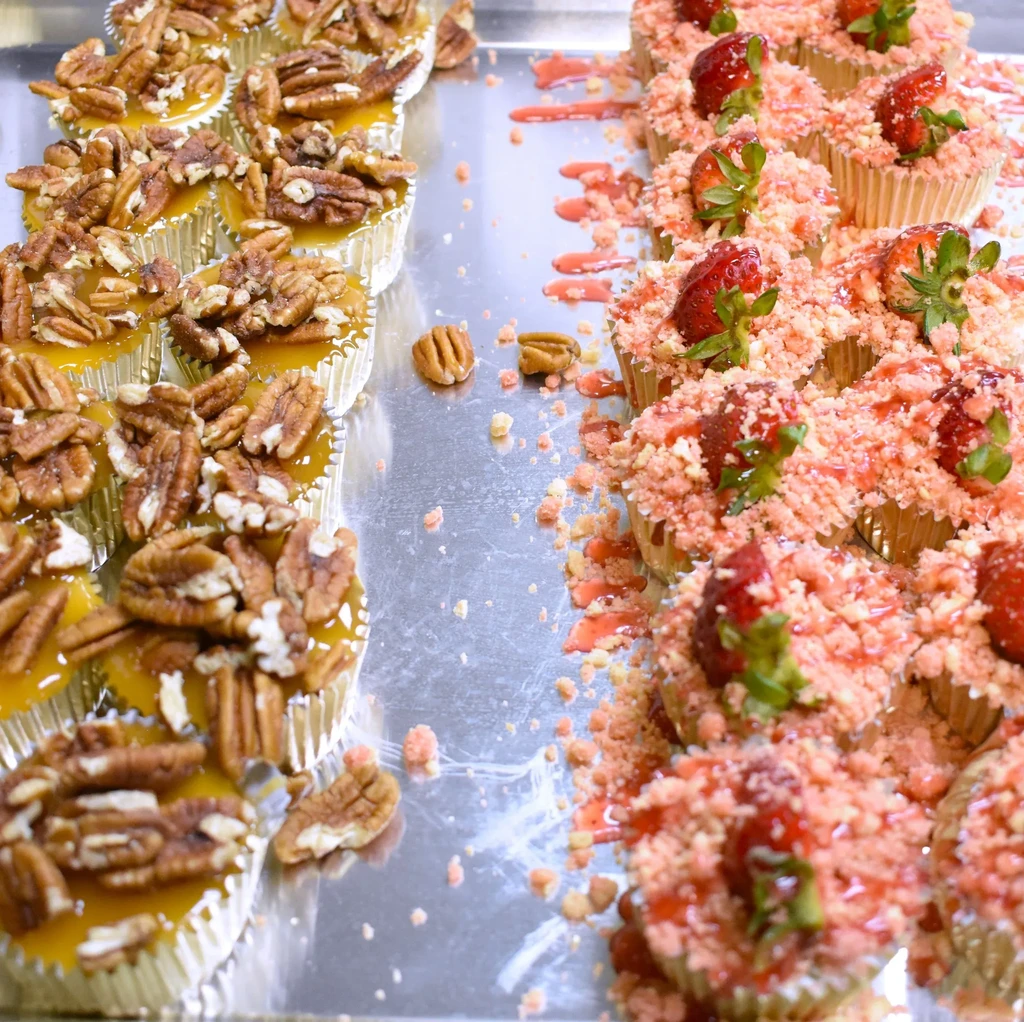 Mini pecan tarts and strawberry crumb desserts on a silver tray.